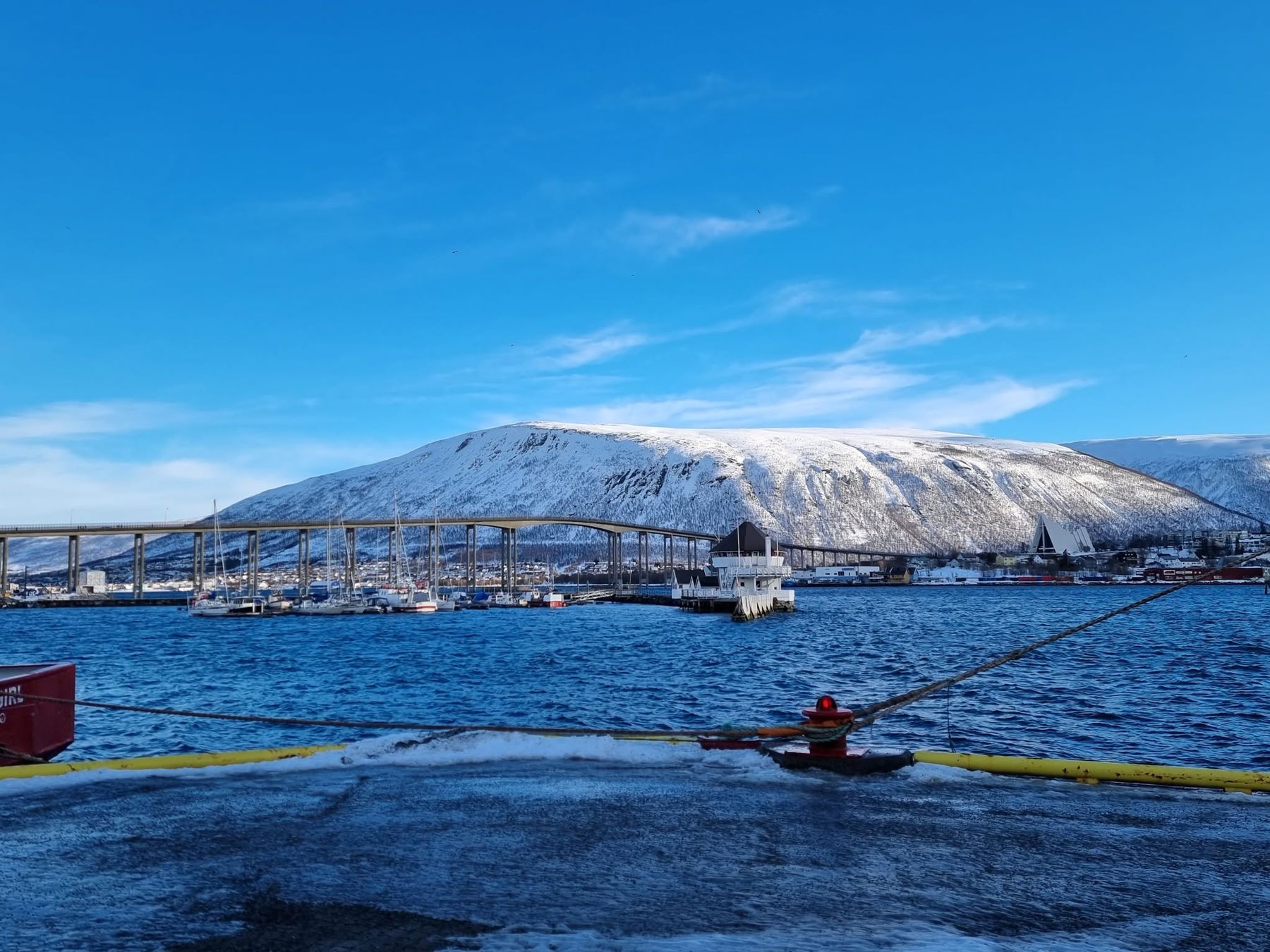 Løkta og båthavna med Tromsøbrua og snødekte fjell en klar vinterdag