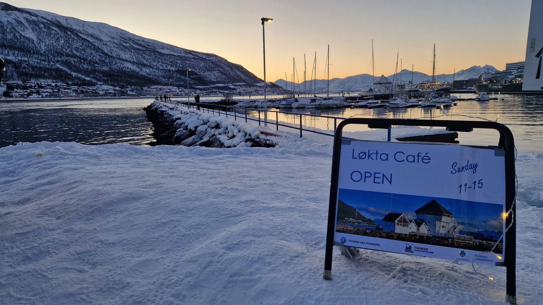 Skilt for Løkta Café i snøen ved moloen